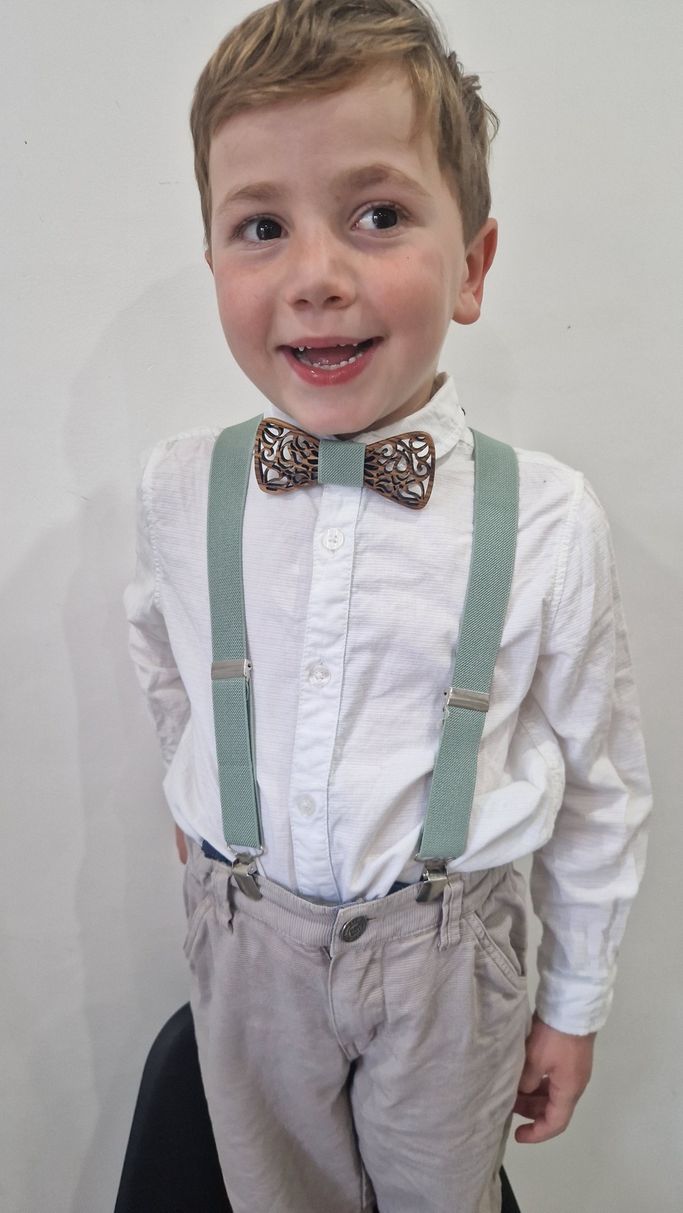 enfant qui porte un noeud papillon en bois et des bretelles